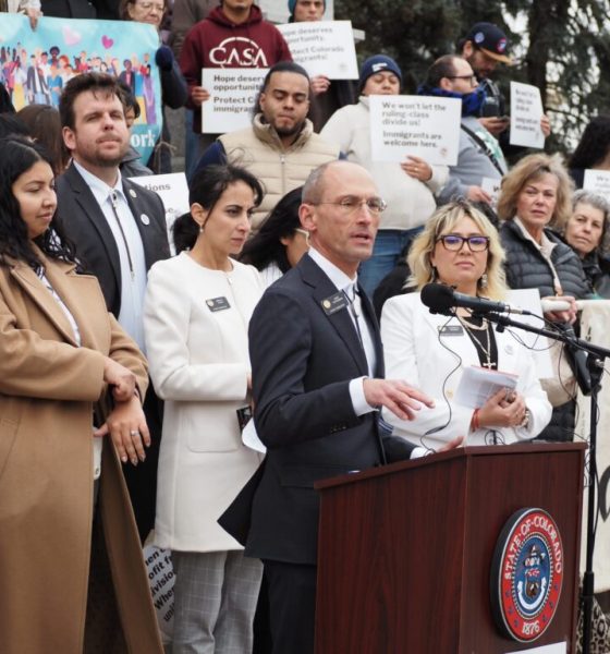 Democratic lawmakers speaking at a press conference with supporters holding signs. — leyes de inmigración