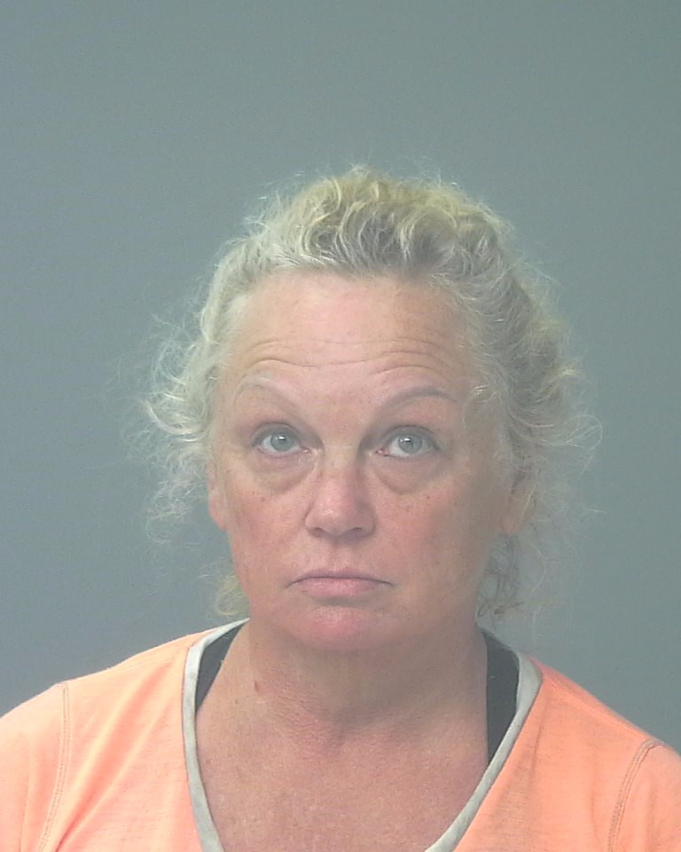 Woman in orange shirt facing camera against gray background