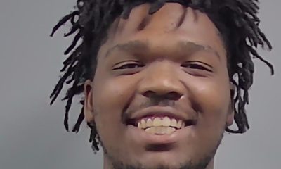 Smiling man with short dreadlocks against gray background