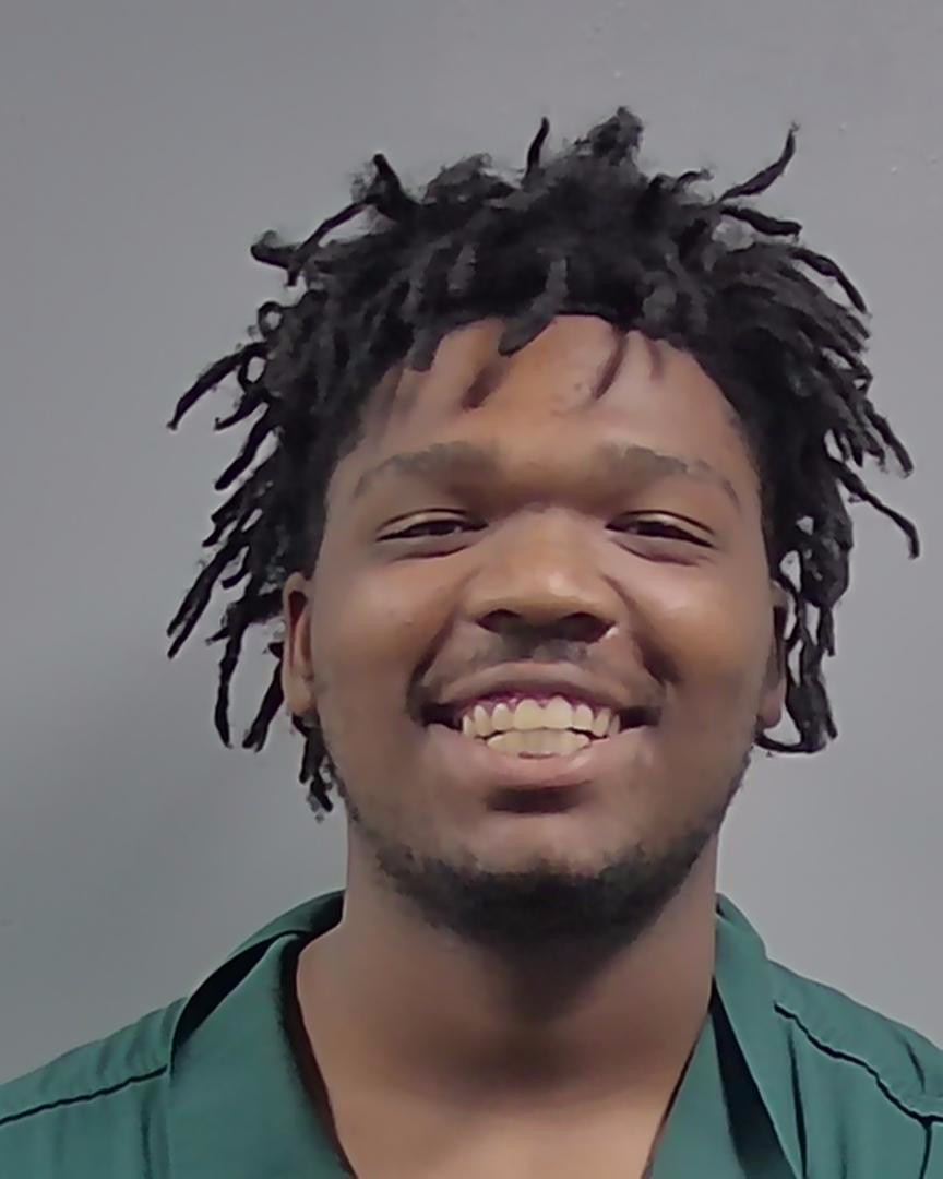 Smiling man with short dreadlocks against gray background