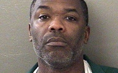Mugshot-style portrait of a man in green shirt