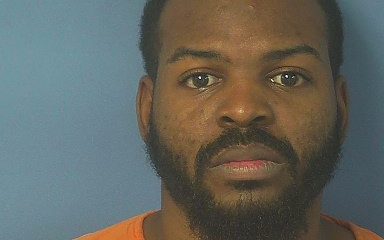 Mugshot-style portrait of bearded man in orange uniform