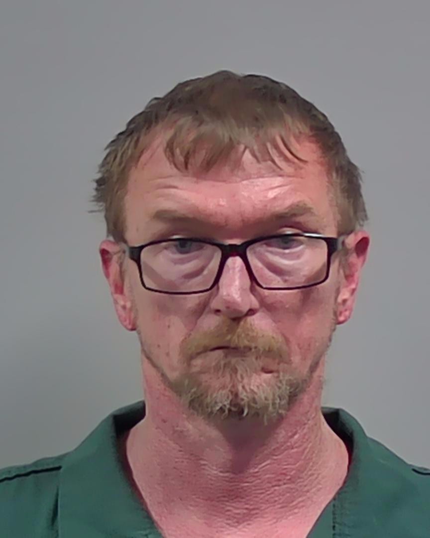 Portrait of a man wearing glasses and a green shirt.