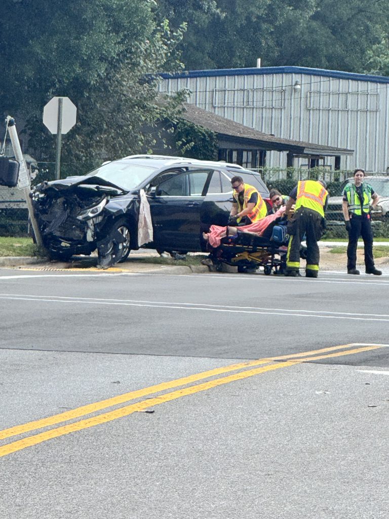 First responders assist crash victim beside severely damaged car