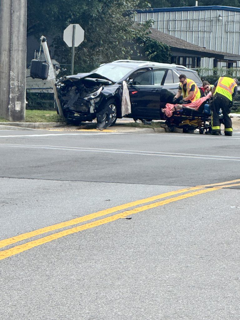 Emergency responders assist beside severely damaged black car