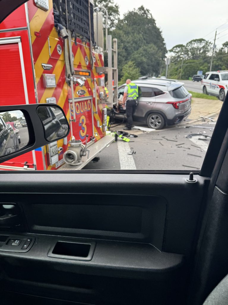 Firefighter works beside red fire truck with open compartment