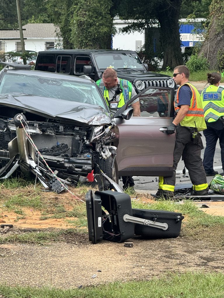 EMS responders assess severely damaged vehicle after roadside crash.