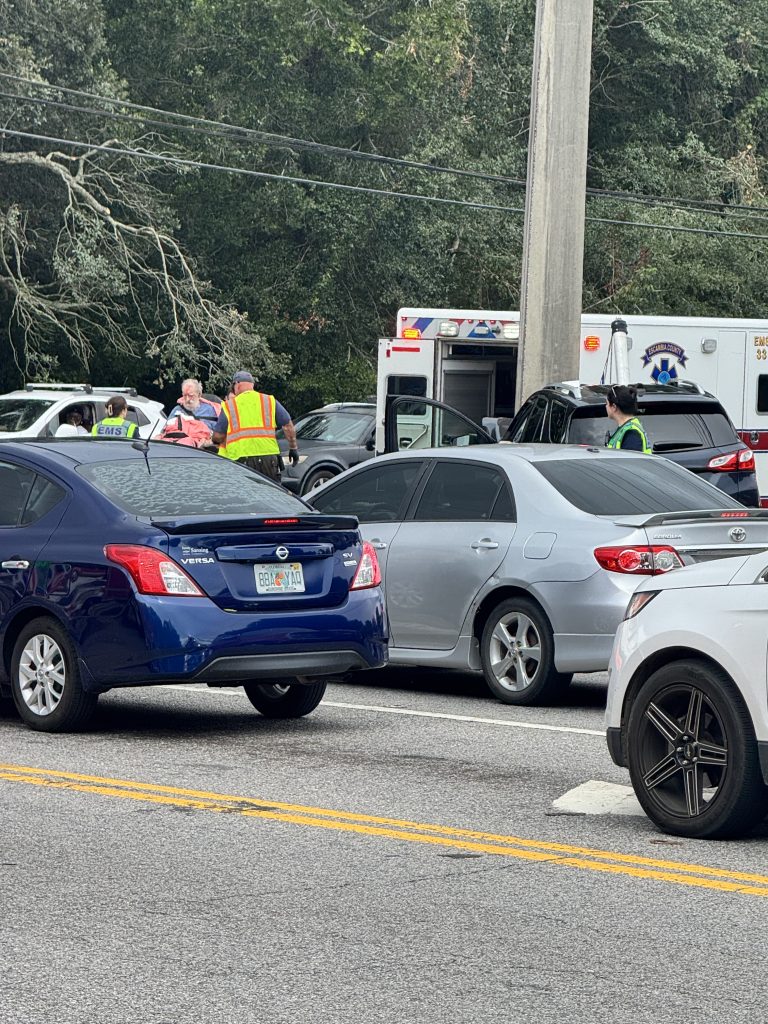 Paramedics assist patient beside ambulance amid stopped traffic
