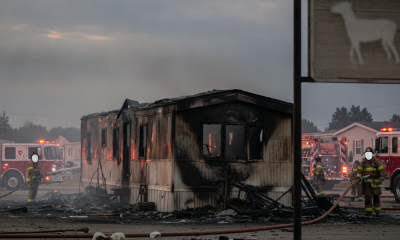Severely damaged mobile home after a fire, with firefighters and emergency vehicles in the b — Cantonment Mobile Home Fire
