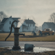 A vintage water pump emits steam in a rural setting, with workers and a truck — Cottage Hill Water Works Boil Water Notice
