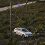 A Lincoln MKX abandoned in a field after a crash near Highway 97, with emergency responders — Highway 97 Crash Walnut Hill