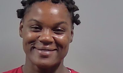 Mugshot of a Lisa Ann Elliot in a red prison uniform with short, curly hair, smiling slightly. — Cantonment shooting arrest