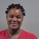 Mugshot of a Lisa Ann Elliot in a red prison uniform with short, curly hair, smiling slightly. — Cantonment shooting arrest