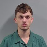 Young man in green uniform against gray background