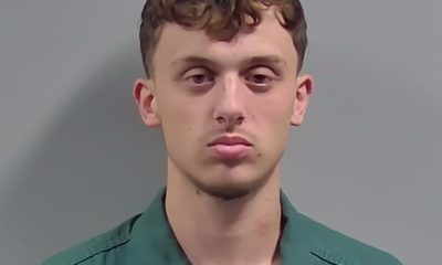 Young man in green uniform against gray background