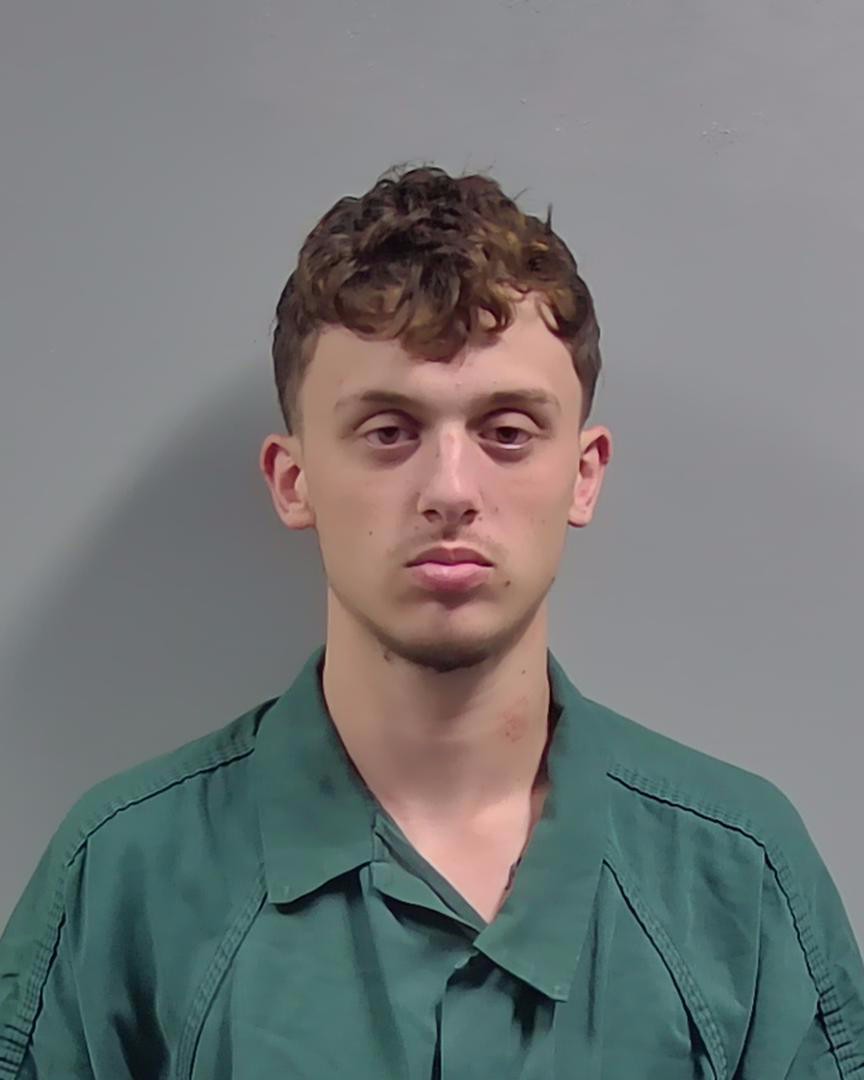 Young man in green uniform against gray background