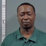 Man in green shirt posed beside height chart — Atmore shooting arrest