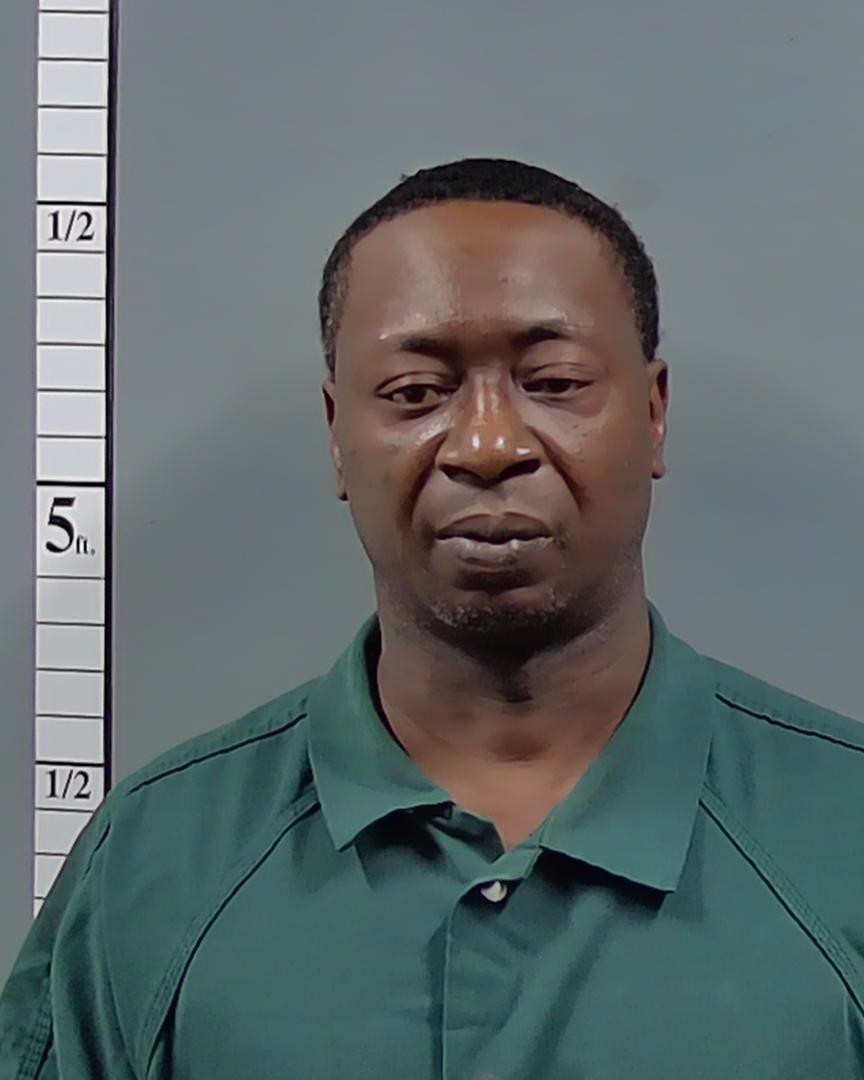Man in green shirt posed beside height chart — Atmore shooting arrest