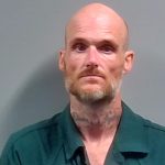 Mugshot of Daniel Eric Slayton, a bald man with facial tattoos, wearing a green prison unifor — Daniel Eric Slayton Arrest