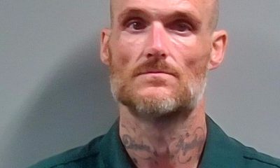 Mugshot of Daniel Eric Slayton, a bald man with facial tattoos, wearing a green prison unifor — Daniel Eric Slayton Arrest