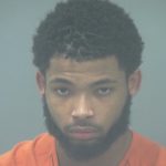 Booking photo of John Charles Newell III, wearing an orange jumpsuit with a serious expression.