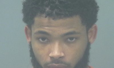 Booking photo of John Charles Newell III, wearing an orange jumpsuit with a serious expression.