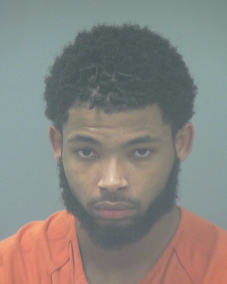 Booking photo of John Charles Newell III, wearing an orange jumpsuit with a serious expression.