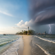Dramatic sky over a beach with a lighthouse, showcasing a storm approaching Pensacola, Florid — Pensacola weather forecast
