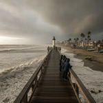 People observing rough seas and dark clouds from a pier during a tropical storm warn — aviso de tormenta tropical escambia