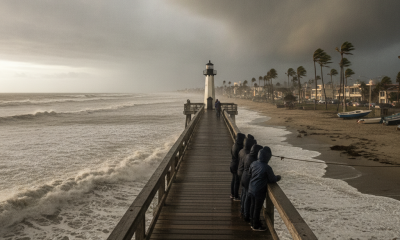 People observing rough seas and dark clouds from a pier during a tropical storm warn — aviso de tormenta tropical escambia
