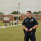 Un oficial de policía de Milton de pie frente al T.R. Jackson Pre-K Center mientras los estudiantes llegan al campus.