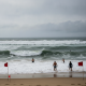 People wading in the ocean near red flags warning of dangerous rip currents in Pensacola. — corrientes de resaca Pensacola