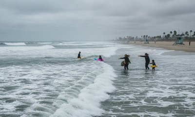 Surfers and beachgoers near turbulent waves on a cloudy day, highlighting the dangers of corrientes de resaca escambia.