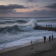Waves crashing against a jetty at sunset, with people observing from the shore, warning fla — corrientes de resaca Florida