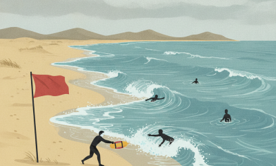 A red warning flag stands on the beach as swimmers face rough surf during a rip current statement.