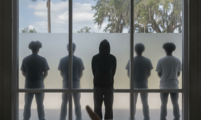 Silhouettes of five people stand behind a glass wall as a hand points toward th — Deshawn Donson Pensacola Armed Robberies