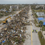 Aerial view of a street covered in hurricane debris with construction equipm — Escambia County Hurricane Damage Assessment