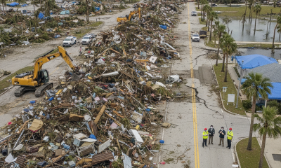 Aerial view of a street covered in hurricane debris with construction equipm — Escambia County Hurricane Damage Assessment
