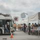 A bus navigating a detour near a food distribution site with volunteers and famil — Escambia County Storm Recovery Updates
