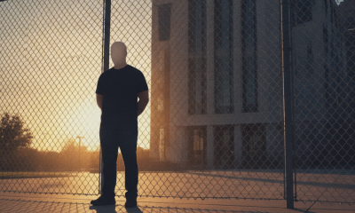 A silhouetted man stands behind a barbed-wire fence outside a prison at sunse — Gainesville Man Fentanyl Overdose Sentence