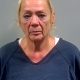 Mugshot of Susanna Marianna Wright, a woman with blonde hair, wearing a blue prison shirt, looking serious.