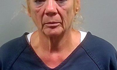 Mugshot of a woman with blonde hair wearing a dark shirt, looking serious against a gray ba — Cantonment Domestic Stabbing