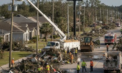Workers and heavy machinery clear debris from a street in Pensacola after Hurricane Isaias, — Pensacola hurricane recovery