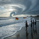 Beachgoers observe warning flags as large waves crash along the shore, indicating rip cur — rip currents Northwest Florida
